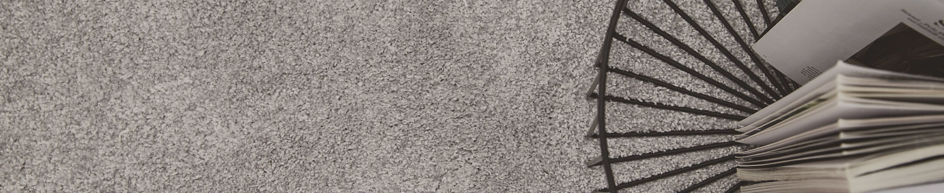 Ein schwarzer Metallkorb hält geöffnete Magazine auf einem grauen Teppichboden.