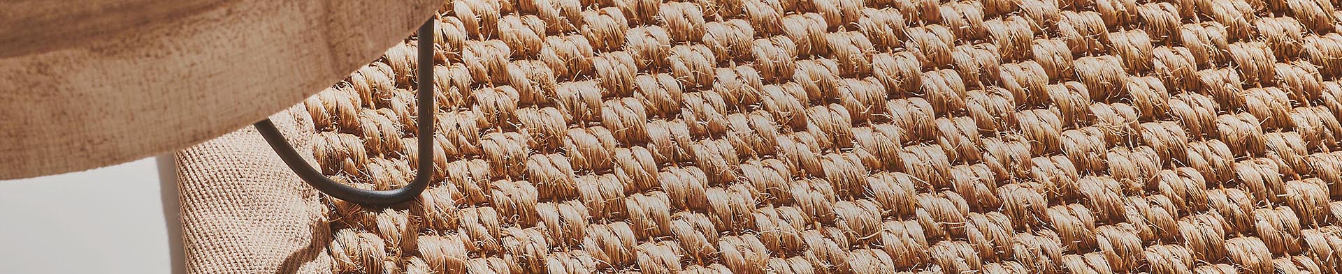 Lampenschirm hängt über geflochtenem Teppich in Innenraum mit hellem Boden.