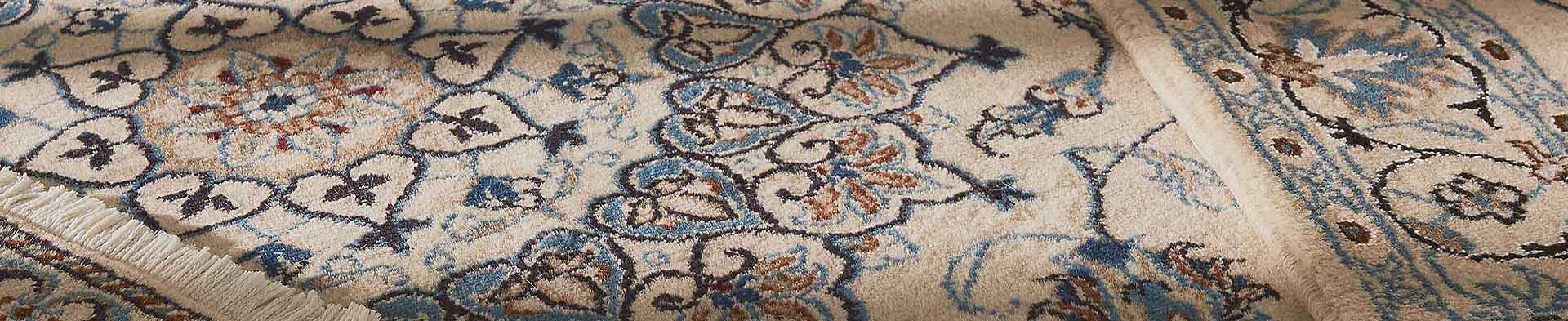 Teppich zeigt florales Muster mit blauen, braunen und schwarzen Akzenten, liegt auf Boden.