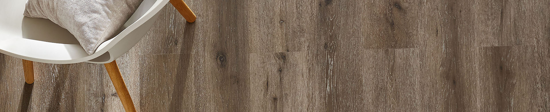 Stuhl mit Kissen steht auf braunem Holzfußboden in einem Innenraum.