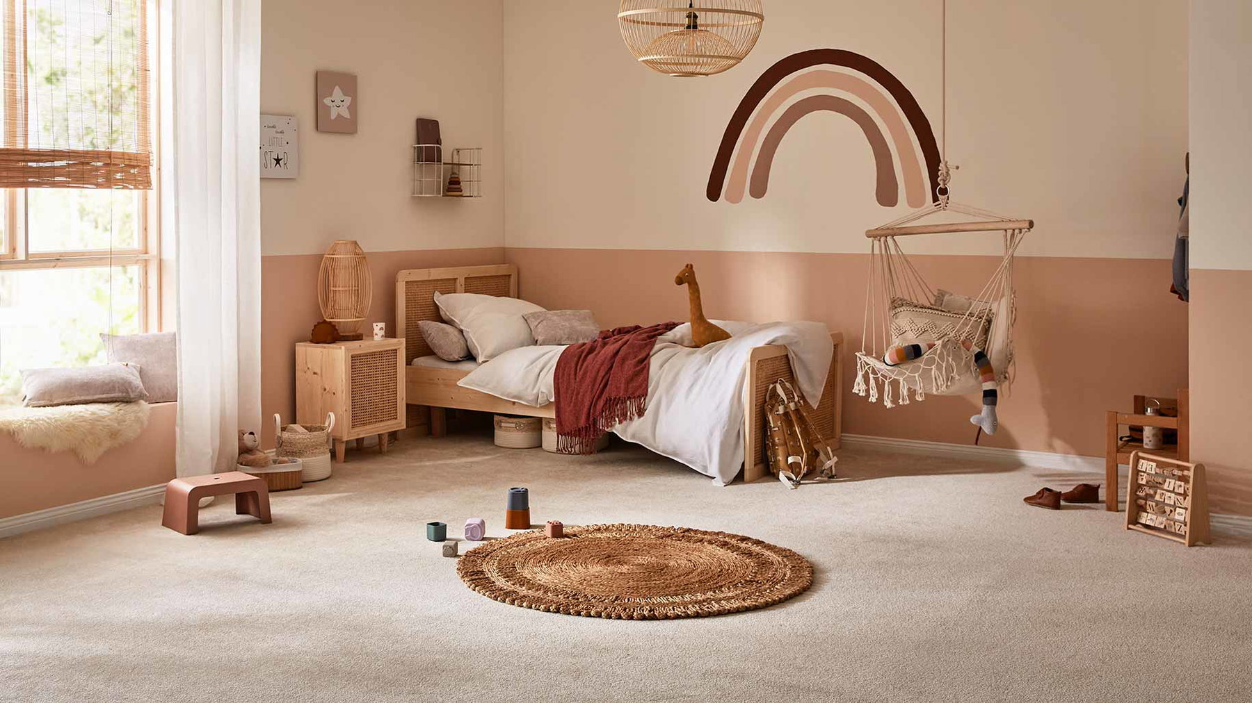 Kinderspielzeug liegt auf rundem Teppich, daneben hängt Schaukelstuhl in hellem Kinderzimmer.