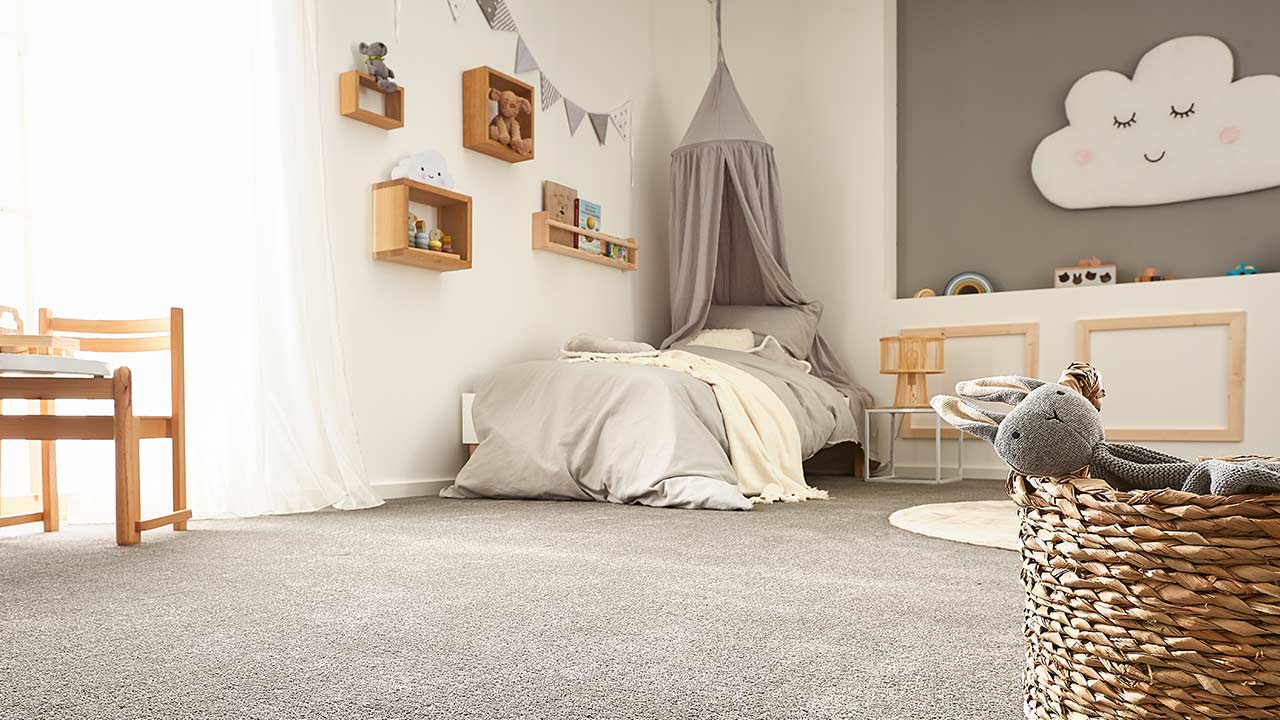 Spielzeugkorb steht im Vordergrund, Bett mit Himmel an Wand im Kinderzimmer.