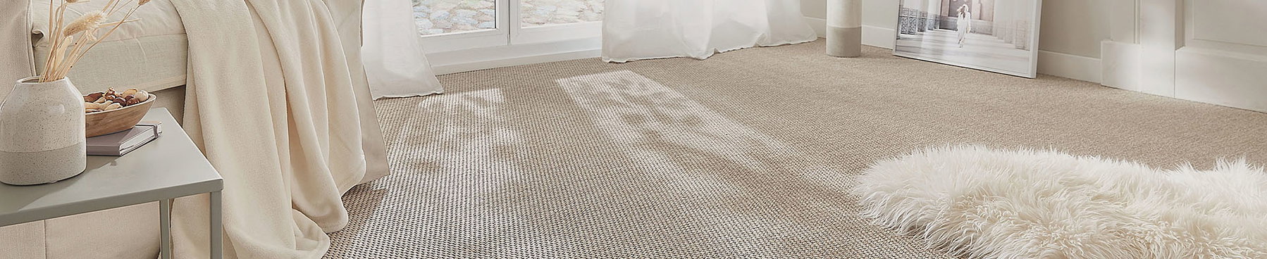 Beiger Teppich bedeckt Boden, Sonnenlicht fällt durch Fenster, weiße Decke und flauschiger Teppich liegen im Raum.