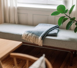 Fensterbank mit grauer Decke, daneben Pflanze, Tageslicht durch Fenster im Wohnraum.