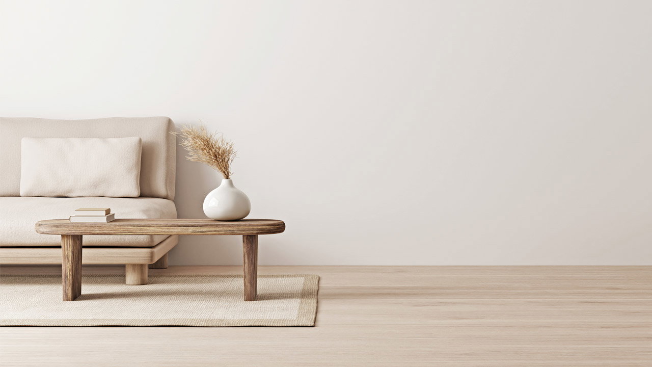 Beiger Sessel steht neben Holztisch mit weißer Vase und getrockneten Pflanzen in minimalistischem Raum.