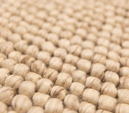 Textil in Wolloptik zeigt dicht gewebte, runde Fasern in hellbeiger Farbe, Nahaufnahme.
