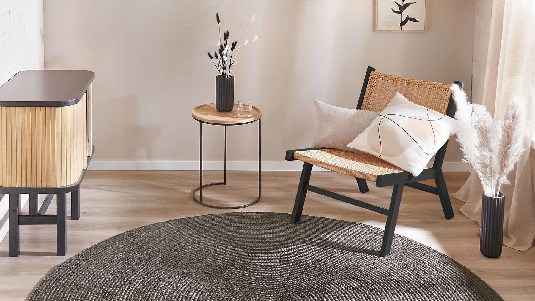 Stuhl steht neben rundem Tisch mit Vase, im hellen Zimmer mit Teppich und Kommode.