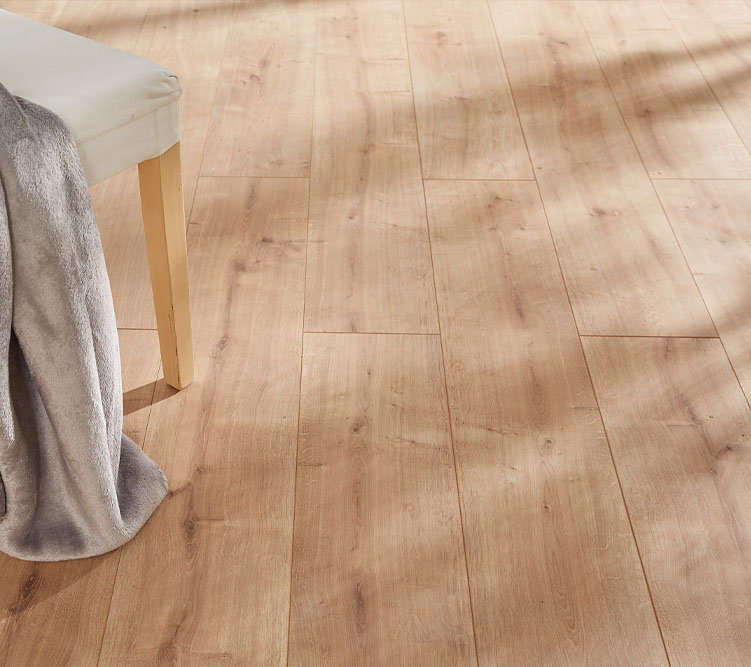 Stuhl steht auf hellem Holzboden, graue Decke hängt seitlich herab, Innenraum mit Tageslicht.