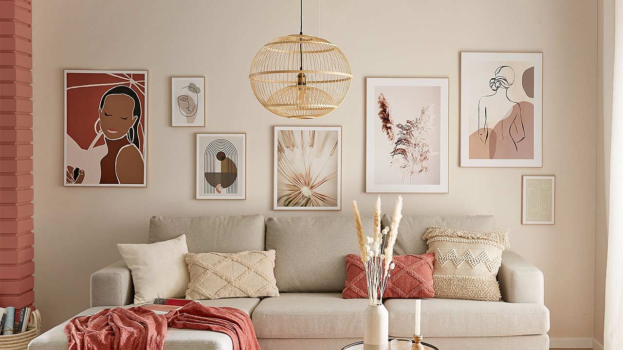 Sofa zeigt Kissen und Decke vor Wand mit sechs gerahmten abstrakten Kunstbildern und Lampe darüber.