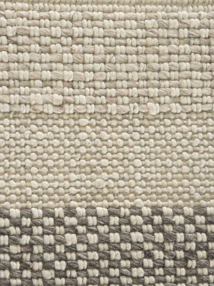 Gewebte textile Fläche zeigt Muster aus hellen und dunklen Fäden in organisierter Struktur.