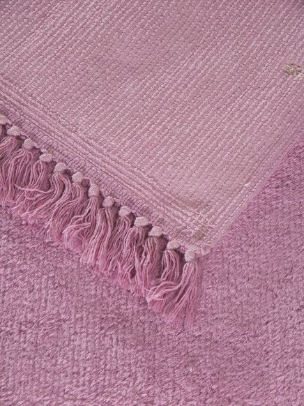 Rosafarbener Teppich liegt auf rosafarbenem flauschigen Teppichboden, Quasten sichtbar.