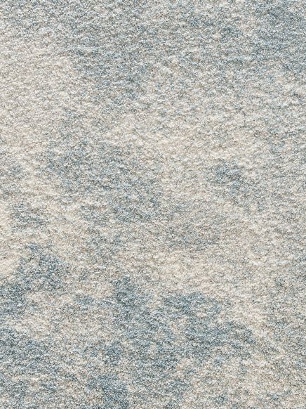 Textiler Teppich zeigt abstraktes Muster in hellen und blauen Farbtönen, Nahaufnahme.