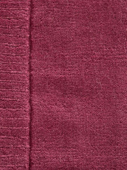 Dunkelroter Strickstoff mit unterschiedlicher Maschenstruktur, links breiter gerippter Rand.