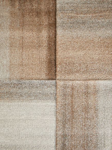 Quadratförmiger Teppich, der aus vier unterschiedlich braun- und beige schattierten Segmenten zusammengesetzt ist.