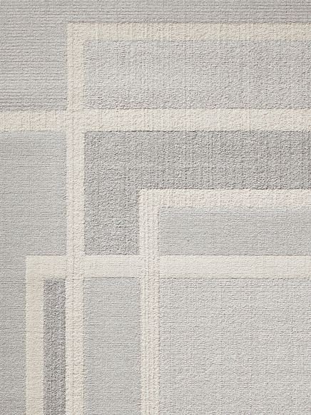 Teppich zeigt geometrisches Muster mit überlappenden Rechtecken in Grau- und Beigetönen.