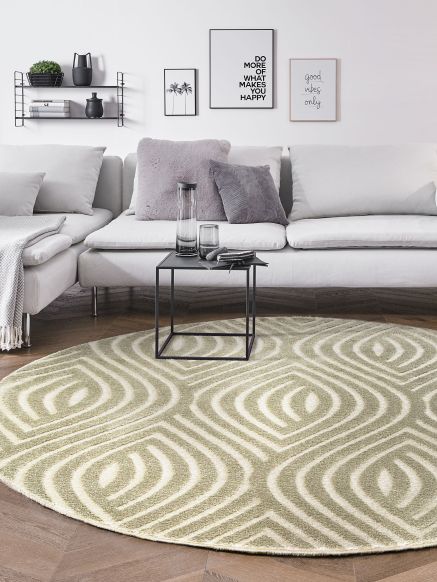 Runder Teppich mit geometrischem Muster liegt vor Sofa mit Kissen und kleinem Tisch im Wohnzimmer.