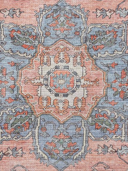 Orientalischer Teppich zeigt geometrisches und florales Muster in Blau und Orange.