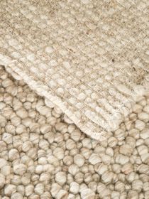 Decke liegt auf grob gewebtem Teppich aus naturfarbenen, dicken Garnknäueln.