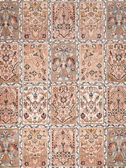 Teppich zeigt rechteckige Muster mit floralen Motiven in Beige, Blau, Rot und Olivfarben.