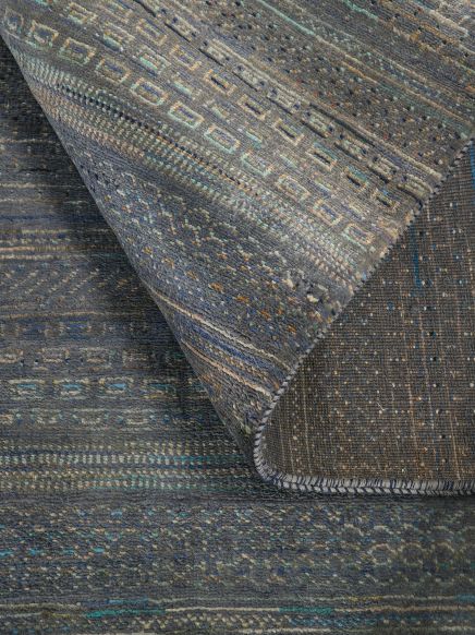 Teppich mit geometrischem Muster faltet sich auf einer Fläche mit ähnlichem Muster.