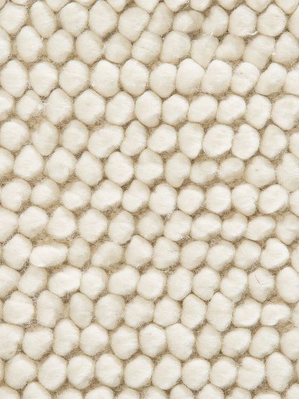 Nahaufnahme von weißen Wollkugeln, die zu einem Teppich verbunden sind.