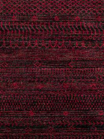 Teppich zeigt rot-schwarzes geometrisches Muster in Streifen auf textiler Oberfläche.