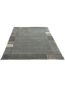 Teppich liegt flach, zeigt graue Grundfläche mit rechteckigem Muster und Details am Rand.