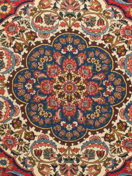 Detailliertes Teppichmuster mit blauen, roten und braunen floralen Motiven in einem symmetrischen Design.