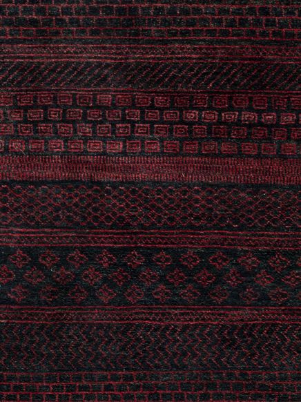 Teppich zeigt rote und schwarze geometrische Muster in verschiedenen Reihen auf dunklem Grund.