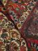 Teppich zeigt florales Muster in Rot, Blau und Beige, eine Ecke ist umgeklappt.