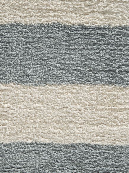 Weicher Teppich zeigt breites Streifenmuster in Grau und Beige, Nahaufnahme auf Boden.