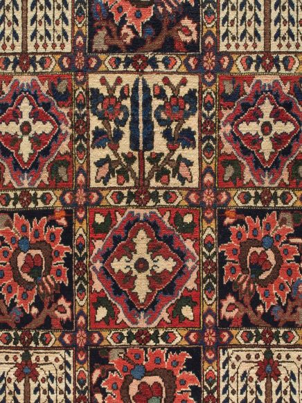 Teppich zeigt quadratische Muster mit floralen und geometrischen Motiven in Rot, Blau, Beige.