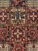 Teppich zeigt quadratische Muster mit floralen und geometrischen Motiven in Rot, Blau, Beige.