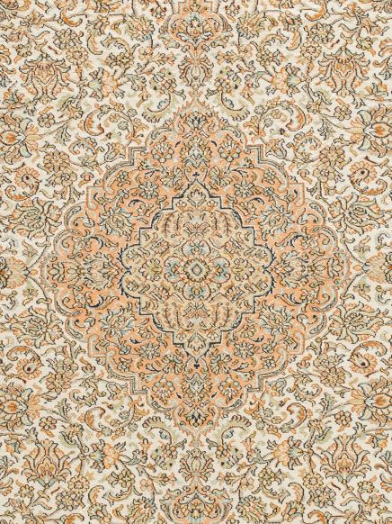 Teppich zeigt zentrales Blumenmuster in Beige, Orange und Hellblau auf hellem Hintergrund.