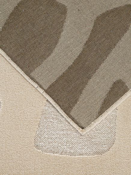 Naht eines Teppichs mit taupefarbenen und beige Streifen auf beigem Untergrund.