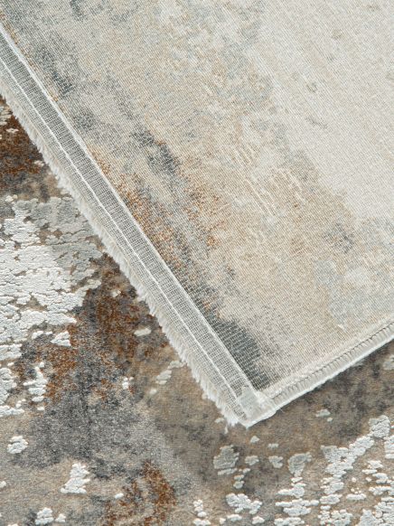 Teppich liegt auf Boden, eine Ecke des Teppichs ist hochgeklappt, um die Rückseite zu zeigen.