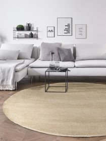 Hellgraues Sofa mit Kissen und Decke, schwarzer Beistelltisch, runder Teppich und Wanddekoration mit Text.