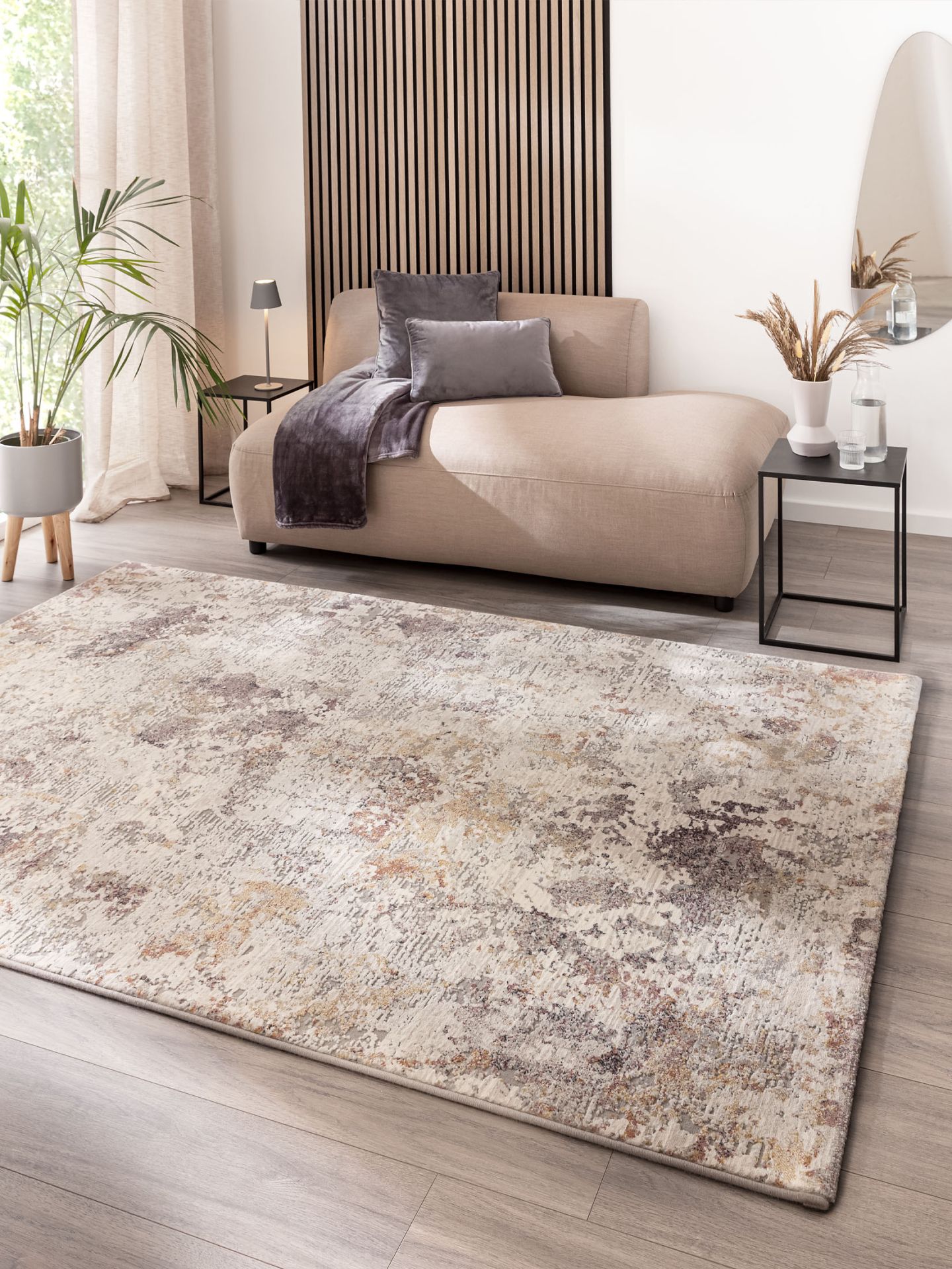 Beiger Teppich liegt auf Holzboden vor beige grauem Sofa mit grauen Kissen in modernem Zimmer.
