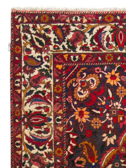 Teppich zeigt florales Muster in Rot, Dunkelblau und Gelb mit Fransen am Rand.