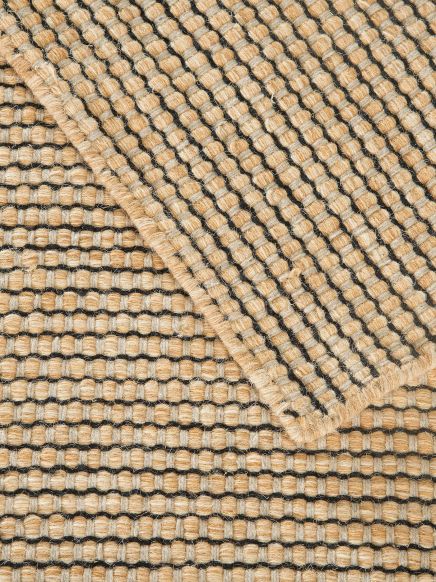 gewebter Teppich zeigt überlappende, beige und schwarze Karomuster in Nahaufnahme