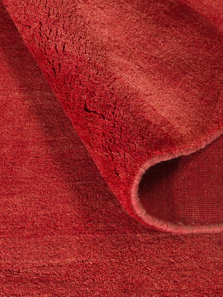 Roter Teppich wird an einer Ecke hochgeklappt, zeigt Rückseite und Oberfläche.