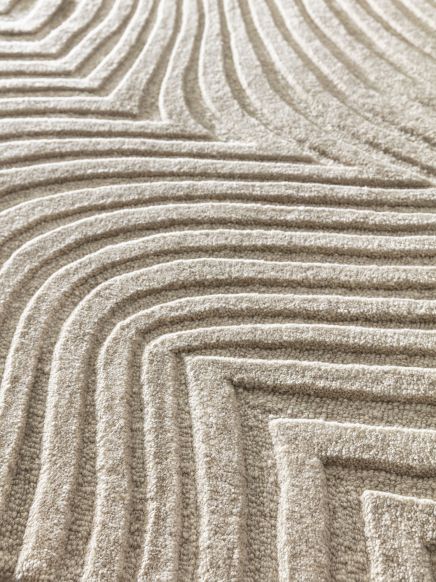 Strukturierter Teppich mit gewellten Linienmuster in natürlichem Beige, Nahaufnahme.