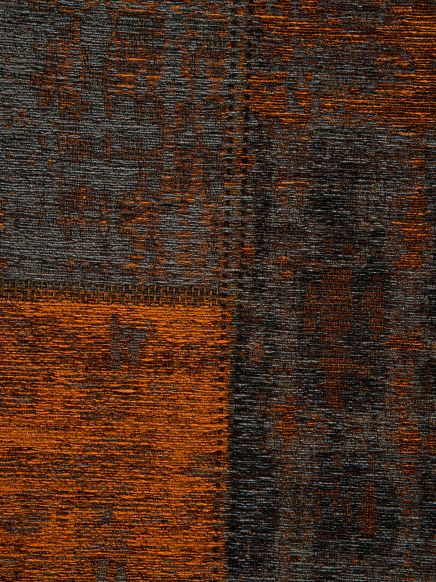 Textiler Teppich zeigt ein geometrisches Muster in orange und grau, aufgenommen in Nahaufnahme.