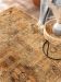 Teppich liegt auf Holzboden, daneben runder Beistelltisch mit Vase und Grau-Decke.