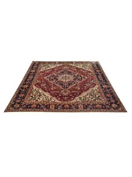 Teppich liegt flach, zeigt florales Muster in Rot, Dunkelblau und Beige, weißer Hintergrund.