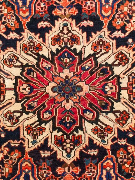 Orientalischer Teppich zeigt rotes, blaues und cremefarbenes geometrisches Muster mit Blumenmotiven.