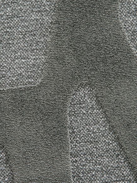 Grauer Teppich zeigt abwechselnd dichte und grobe Strukturen in geometrischen Formen.
