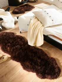 Brauner Teppich liegt auf Holzfußboden neben Bett mit beige Decke in hellem Raum.