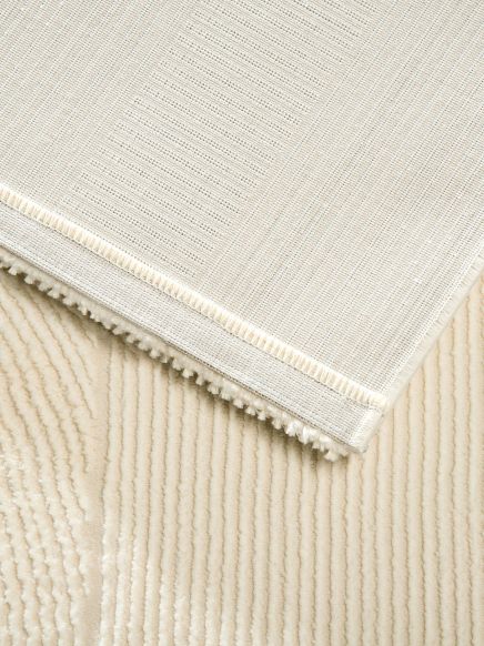 Teppich liegt auf einem weich strukturierten cremefarbenen Boden mit Linienmuster.