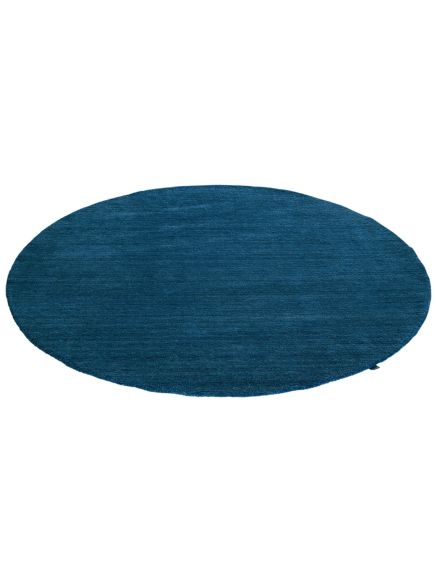 Runder, blauer Teppich liegt flach auf weißem Hintergrund ohne weitere Objekte.